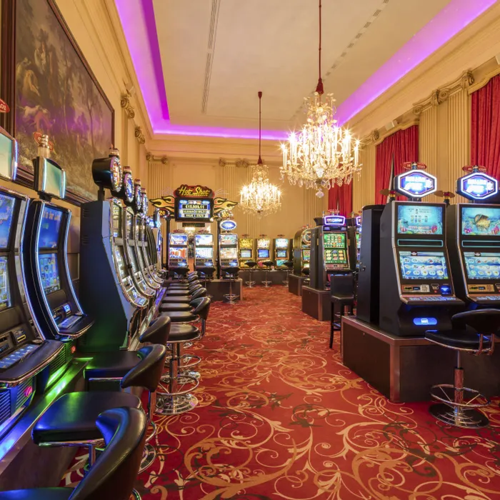 Luxuriöses Casino mit Reihen von Spielautomaten, rotem Teppich und Kronleuchtern